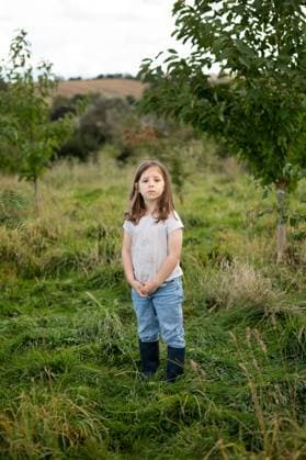 Creative Highlight Symbolbilder Young girl standing alone in a wild orchard. Corby, England, United Kingdom R_JNDO250728-1796000-01 ,model released, Symbolfoto