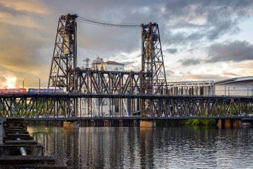 Steel Bridge in Portland, Oregon, at sunset with reflections on the river and a train crossing. 33241853 RECORD DATE NOT STATED