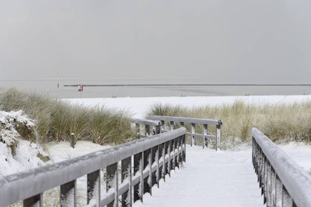 IMAGO Creative, Winter, Auf dem Land Wintertag, Wintereinbruch, Holzbohlenweg führt durch die verschneite Dünenlandschaft zur Nordsee, Norddeich, Niedersachsen, Deutschland Winter day, onset of winter, wooden plank path leads through the snow-covered dune landscape to the North Sea, Norddeich, Lower Saxony, Germany Copyright: imageBROKER Frederik ibxrba14523084.jpg