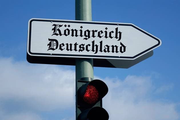 Wegweiser zum Königreich Deutschland und rote Ampel Fotomontage: Wegweiser zum Königreich Deutschland und rote Ampel, 08.08.2025, Über einer roten Ampel befindet sich ein Wegweiser mit dem Schriftzug Königreich Deutschland. *** Signpost to the Kingdom of Germany and red traffic light Photomontage Signpost to the Kingdom of Germany and red traffic light, 08 08 2025, Above a red traffic light is a signpost with the lettering Kingdom of Germany