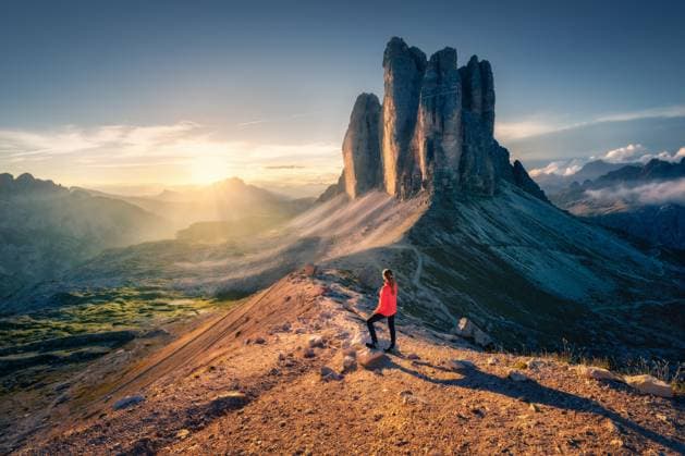 Creative Highlights Symbolbilder Female hiker enjoying the breathtaking sunrise over the Tre Cime di Lavaredo, three striking peaks rising majestically in the Dolomites, Italy. Landscape with woman, trail, rocks. Trekking and hiking Model Released DenisBilytskyi_ID30691_1038784_032 Copyright: xx