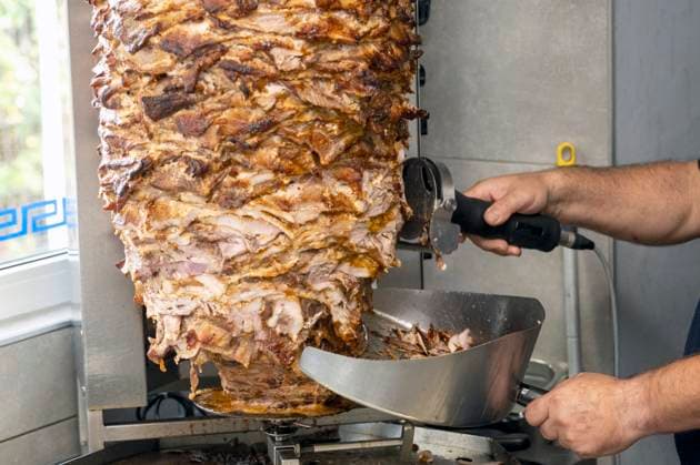IMAGO Creative, Food, Fast Food, Döner Gyros- Dönerspieß Ein großer, saftig gebratener Döner-Kebab Gyros-Spieß steht in einem Imbiss vor dem Grill. Die goldbraun gerösteten Fleischschichten türmen sich in der vertikalen Rotisserie, bereit für den Anschnitt. Durch das Fenster im Hintergrund scheint Tageslicht, während in der Gastronomie steigende Kosten den beliebten Imbissklassiker zunehmend verteuern. Veröffentlichungen nur für redaktionelle Zwecke. Foto: FotoPrensa Essen *** Gyros kebab skewer A large, juicy roasted kebab gyros skewer stands in front of the grill in a snack bar The golden-brown roasted layers of meat are piled up in the vertical rotisserie, ready to be cut Daylight shines through the window in the background, while rising costs in the catering