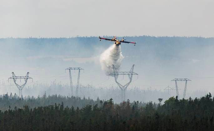 August 14, 2025, St. John s, Nl, CANADA: A water bomber provides a steady steam of water to assist crews on the ground at the Paddy s Pond wildfire, just outside St. John s, N.L., on Thursday, Aug. 14, 2025. St. John s CANADA  - ZUMAc35_ 20250814_zaf_c35_068 Copyright: xPaulxDalyx
