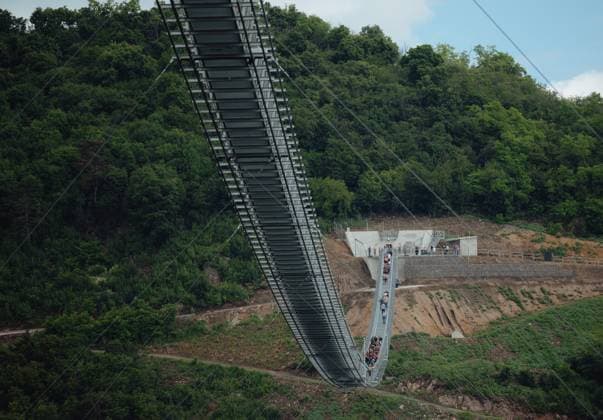 Longest two-way suspension bridge opens to the public for the first time in Hungary SATORALJAUJHELY, HUNGARY - JUNE 5: Visitors of the world s longest two-way suspension bridge cross the structure for the very first time, which was opened to the public on 5th June 2024, in Satoraljaujhely, Hungary. The nearly 800-meter-long structure connects the two points of the city, Var-Hill and Szar-Hill, at a height of 80 meters. The bridge, which will have a glass floor in the central part, is being built as part of the Tokaj-Zemplen Development Programme, with a budget of £9.3 million (HUF 4 billion). The walkway will have a width of 1.2m and descend by 27m at its lowest point, resulting in a 15% steepness at its most extreme. The design of bridge p  Copyright: x2025xAnadoluxRobertxNemetix