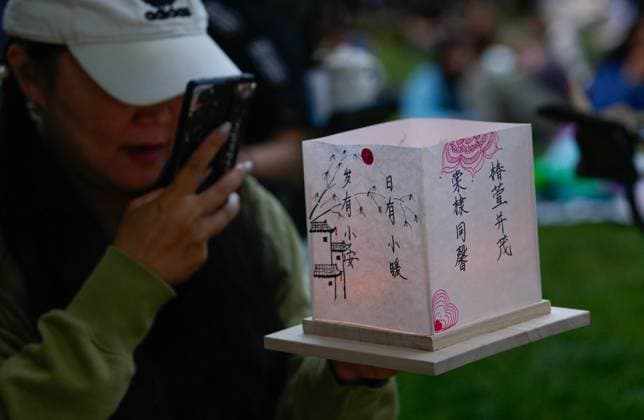 (250817) -- COQUITLAM, Aug. 17, 2025 -- A woman takes photos of her water lantern during the Water Lantern Festival in Coquitlam, British Columbia, Canada, Aug. 16, 2025. The event attracted hundreds of residents and visitors to enjoy the illuminated lanterns and share wishes for hope and joy. (Photo by Xinhua) CANADA-COQUITLAM-WATER LANTERN FESTIVAL LiangxSen 