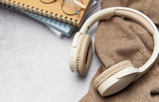 Beige wireless headphones, eyeglasses and notebooks on a cozy sweater evoke feelings of relaxation and learning Model Released OlenaRudo_ID30588_1034108_027 Copyright: xOlenaxRudox