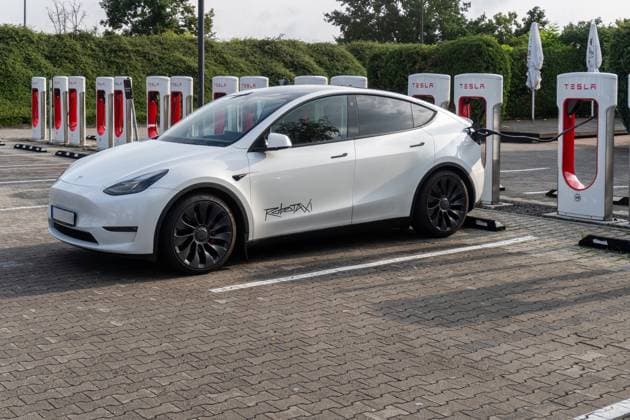 FOTOMONTAGE AUFKLEBER, Ein Tesla mit Robotaxi Sticker lädt am Supercharger Sinnbild für autonome Mobilität, Elektromobilität und Innovation. Die Verbindung aus Technologie und Nachhaltigkeit prägt die Zukunft des Fahrens