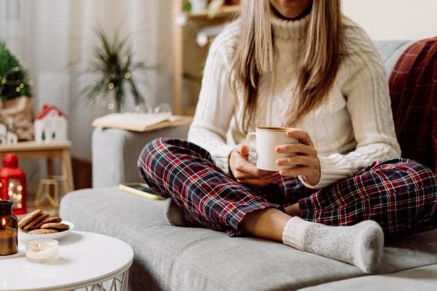 Cozy woman legs in knitted winter warm socks, sweater and checkered plaid drinking hot cocoa or coffee in mug, during resting on couch at home. Christmas holidays with candle, decor and cookies. Cozy woman legs in knitted winter warm socks, sweater and checkered plaid drinking hot cocoa or coffee in mug, during resting on couch at home. Christmas holidays with candle, decor and cookies, model released, , 63242568.jpg RECORD DATE NOT STATED