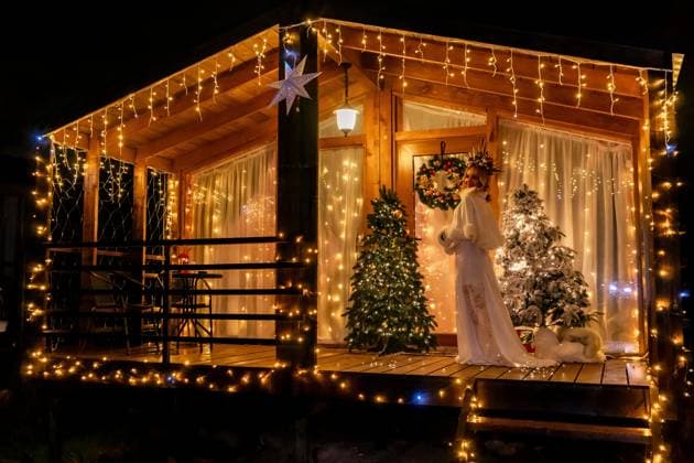 Christmas Lights Cabin Decorated Holiday Season A small wooden cabin decorated for Christmas with lights, a wreath, and two Christmas trees. The cabin is lit up and appears festive., model released, , 63275686.jpg RECORD DATE NOT STATED