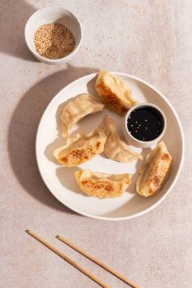 IMAGO Creative, Food, Dumplings Top view of chicken vegetable gyozas on white plate Top view of golden-brown chicken and vegetable gyozas served on a white plate with a small bowl of soy sauce. Background features light stone surface and chopsticks. Model Released MaiderAlvarez_ID30883_1046944_003 Copyright: xMaiderxAlvarezx