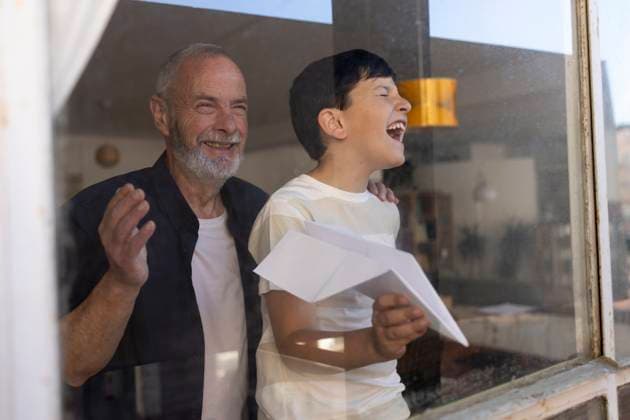 Creative Highlight Symbolbilder Grandfather and grandson playing with paper plane indoors by window model released, Symbolfoto property released, ALZF01379