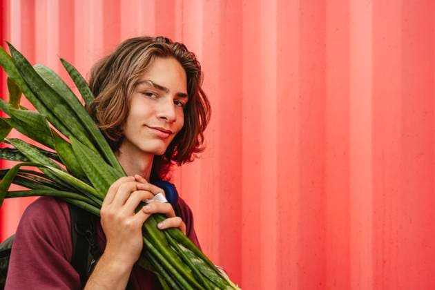 Creative Highlight Symbolbilder Portrait of person holding Sansevieria plant against red wall model released, Symbolfoto, IHF02286