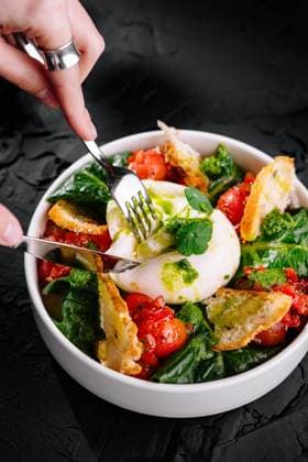 Frischer Burrata-Käse-Salat mit Tomaten und Spinat Bowl of burrata cheese salad, with ripe tomatoes, spinach, and crispy bread on black background (License=RF) Copyright: xZoonar.com AntonxDobreax 23888900