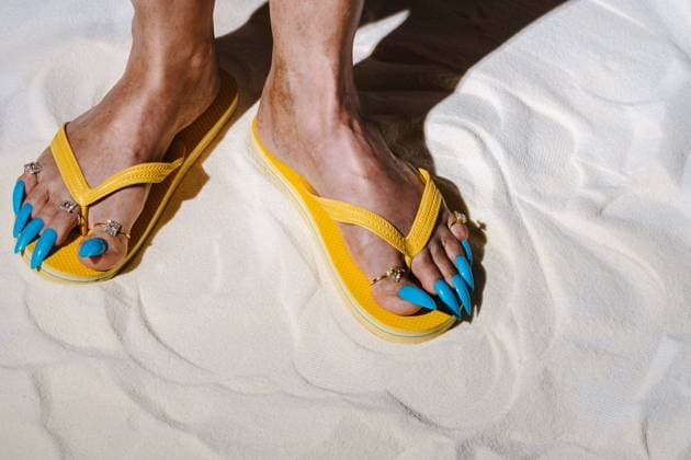 Creative Highlight Symbolbilder Yellow sandals and blue false nails on sand with playful summer vibe model released, Symbolfoto, AAF00104