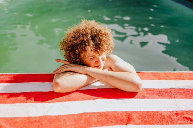 Creative Highlight Symbolbilder Teen with curly hair relaxing on striped towel by pool outdoors model released, Symbolfoto property released, MDOF02962