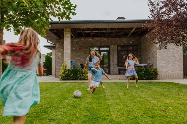 Family playing football together on grass lawn outside home in summer model released, Symbolfoto property released, MDOF02977