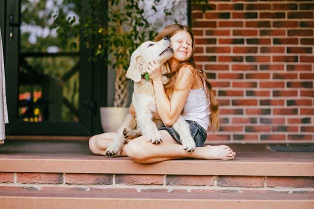 Girl hugging Golden Retriever puppy on home porch showing affection model released, Symbolfoto property released, MDOF03044