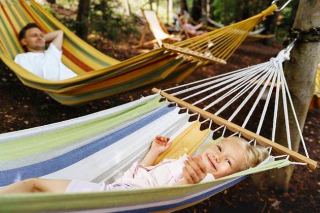 Smiling girl relaxing in hammock with man outdoors in forest model released, Symbolfoto, NSTF00556