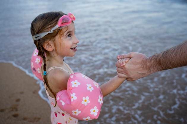 Creative Highlight Symbolbilder Child with swim float holding parent s hand at the beach model released, Symbolfoto, OGSF00180