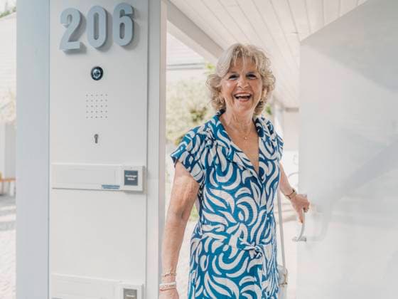 Creative Highlight Symbolbilder Smiling woman welcoming guest at modern home entrance in summer model released, Symbolfoto property released, MFF09614