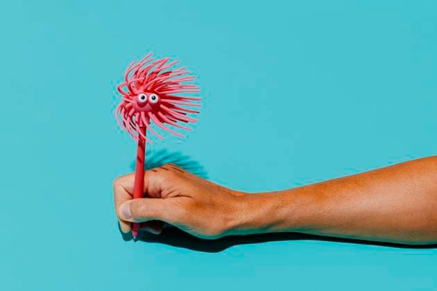 Creative Highlight Symbolbilder Hand holding pink novelty pen in playful mood against blue background model released, Symbolfoto, JMYF00146