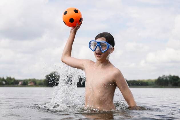 Creative Highlight Symbolbilder Young swimmer with ball and mask playing in the lake outdoors model released, Symbolfoto, EYAF03510