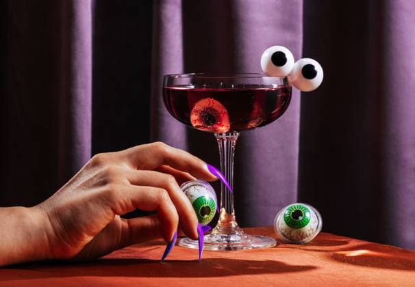 Creative Highlight Symbolbilder Female witch hand with fake nails holding eyeball by purple cocktail model released, Symbolfoto, AAF00157