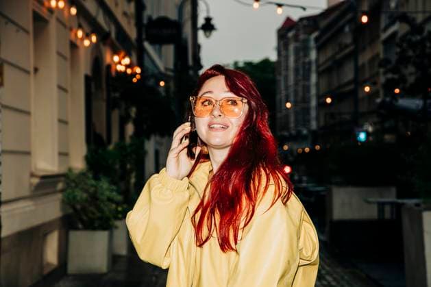 Creative Highlight Symbolbilder Red haired person with yellow jacket talking on smartphone in city evening model released, Symbolfoto, VSNF03775