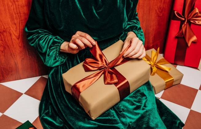 Stylish woman in green dress wrapping Christmas gift on retro floor model released, Symbolfoto, VSNF03937