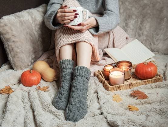 Cozy home, woman covered with warm blanket, drinks coffee. Autumn pumpkins and candles next to woman. Relax, carefree, comfort lifestyle. Model Released OlenaRudo_ID31173_1057308_026 Copyright: xx