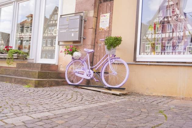 Ein lila Fahrrad mit Blumenkorb vor einem Gebäude mit Fachwerkhäusern, Kleinstadt Perle Calw, Schwarzwald, Deutschland A purple bicycle with a basket of flowers in front of a building with half-timbered houses, small town of Perle Calw, Black Forest, Germany Copyright: imageBROKER ManuelxKamuf iblmlk14784732.jpg