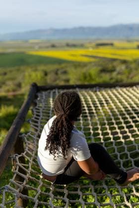 Girl on a cargo net deep in thought South Africa, Western Cape, Porterville R_YNJN250821-1808954-01 ,model released, Symbolfoto