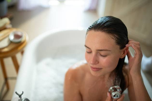 Relaxed young woman enjoying self-care and hair wash in bathtub. Relaxed young woman enjoying self-care and hair wash in bathtub, peaceful self-ritual. model released