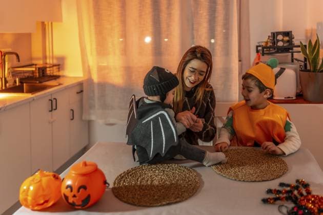 Mutter und Kinder in Halloween Kostümen sitzen an einem Tisch in der Küche, spielen und lächeln Mother and children wearing halloween costumes are sitting at a table in the kitchen, playing and smiling Copyright: imageBROKER UnaixHuizi ibxuhu14805326.jpg ,model released, Symbolfoto ,property released