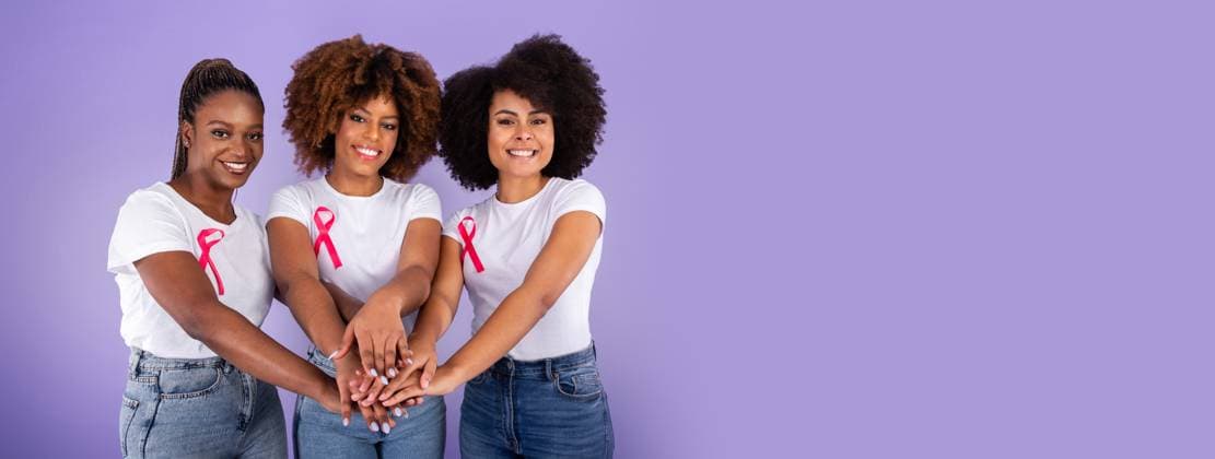 Three Black Ladies With Pink Ribbons Joining Hands, Purple Background Breast Cancer Awareness. Three Smiling Black Ladies With Pink Ribbons Joining Hands In Stack Over Purple Studio Background. Fighting Oncology Together Concept, Support Group, model released, , 63138806.jpg RECORD DATE NOT STATED