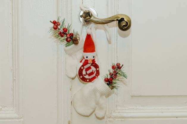 Small mittens with a Christmas tree branch and a snowman hang on the door handle. Children s mittens with a Christmas tree branch and snowman decor hang on the retro handle of a white door in a home office during the day, side view very close up. New Year concept, Merry Christmas, holiday decor., 63408708.jpg RECORD DATE NOT STATED