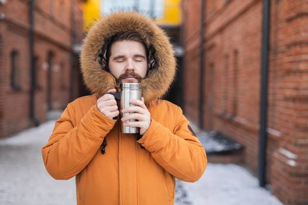 Man in winter parka holds thermos with closed eyes on snowy urban street. Warmth, solitude, and comfort in cold weather. Man in winter parka holds thermos with closed eyes on snowy urban street. Warmth, solitude, and comfort in cold weather, model released, , 95622650.jpg RECORD DATE NOT STATED