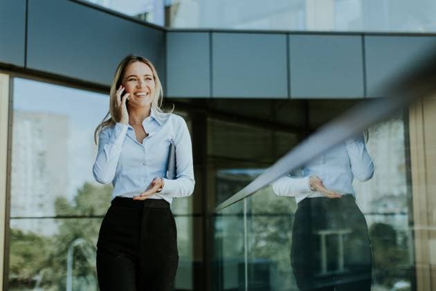 Confident businesswoman chatting on phone in modern office building during day A young businesswoman smiles confidently while talking on her phone inside a sleek, modern office building, with cityscape reflections in the glass., model released, , 95293462.jpg RECORD DATE NOT STATED