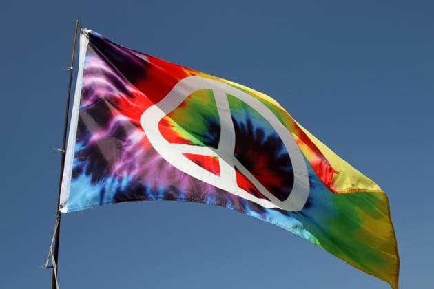 WOODSTOCK FOREVER FESTIVAL 2025 vom 13. bis 17. August 2025 unter dem Motto: 5 DAYS LOVE PEACE MUSIC in Waffenrod, Thüringen, Deutschland, GER - Impressionen vom Festivalgelände. Bunte Peace-Fahne weht auf dem Campinggelände des Festivals. WOODSTOCK FOREVER ist ein Hippie-Musikfestival und Happening mit vielen nationalen und internationalen Bands und Musikern am Rande der thüringischen Ortschaft Waffenrod und wurde erstmals im Jahr 2003 veranstaltet. Das Festival ist bekannt für seinen familiären Charakter. Zahlreiche Besucher übernachten auf dem Festivalgelände in ihren Zelten, Wohnwagen und Campingbussen. Fliegende Händler umsorgen die Festivalgemeinde.