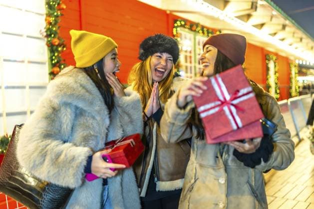 Drei fröhliche Frauen tauschen auf einem dekorierten Nachtmarkt Weihnachtsgeschenke aus und genießen die festliche Atmosphäre Three cheerful women exchanging christmas presents at a decorated outdoor night market, enjoying the festive atmosphere Copyright: imageBROKER UnaixHuizi ibxuhu14839081.jpg ,model released, Symbolfoto ,property released