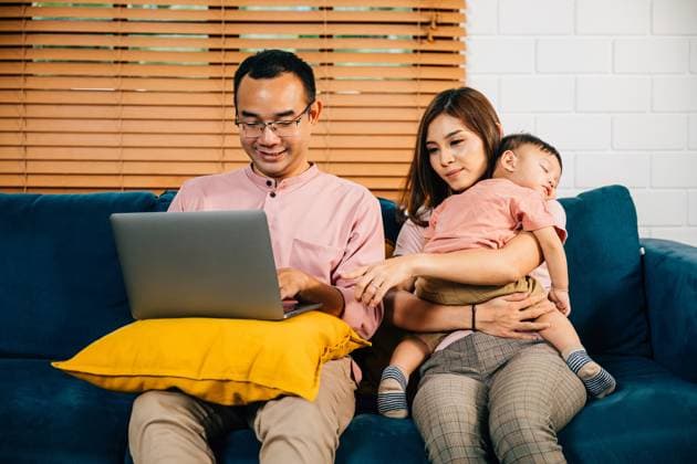 A businesswoman carries her sleeping daughter while her husband works on a laptop A businesswoman carries her sleeping daughter while her husband diligently works on a laptop in their home office. Balancing work family and bonding this portrait radiates responsibility and love., model released, , 95833682.jpg RECORD DATE NOT STATED