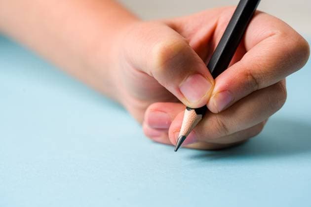 Left hand holding a ballpoint pen on an open notebook on a blue background Left hand holding a ballpoint pen on an open notebook on a blue background, 95921294.jpg RECORD DATE NOT STATED