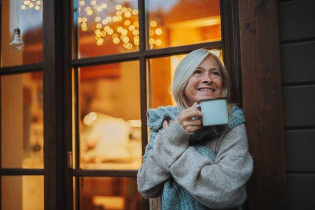 Senior woman enjoying warm tea on terrace during cold autumn evening. Senior woman enjoying warm tea on terrace during cold autumn evening. Indian summer hygge. model released