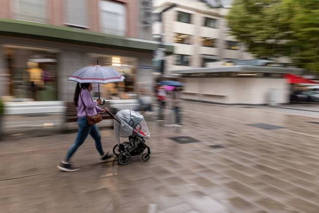 Frau mit Kinderwagen im Regen 09.09.25, Limburg: Symbolfoto, Illustrationsbild, Symbolbild, Illustrationsfoto, Alltagsszene Eine Frau schiebt mit einem Kinderwagen durch eine nasse Einkaufsstraße. Sie hält einen bunten Regenschirm und bewegt sich zügig, während die Umgebung in Bewegungsunschärfe verschwimmt. Das Bild zeigt eine Alltagsszene bei Regenwetter in urbaner Umgebung. Limburg Hessen Deutschland *** Woman with stroller in the rain 09 09 25, Limburg Symbol photo, illustration image, symbol image, illustration photo, everyday scene A woman pushes a stroller through a wet shopping street She holds a colorful umbrella and moves briskly while the surroundings blur in motion The picture shows an everyday scene in rainy weather in Copyright: xThorstenxWagnerx
