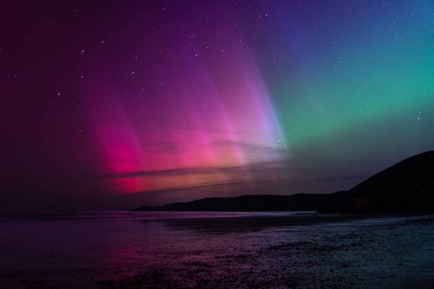 Vibrant northern lights over a dark coastal landscape at night Newgale, Wales, United Kingdom CR_BPXB250908A-1827218-01