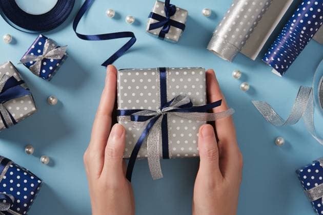 Hands hold a silver-colored gift box. Around it are gifts and ribbons in blue and silver colors. Hands hold a silver-colored gift box. Around it are gifts and ribbons in blue and silver colors., 97738616.jpg RECORD DATE NOT STATED