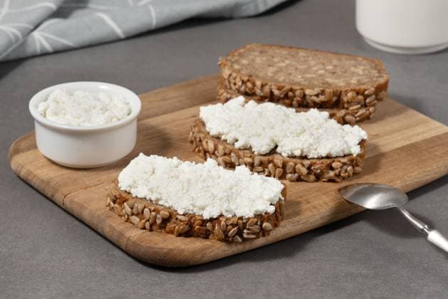 Delicious rye bread topped with cottage cheese on a wooden board in a modern kitchen setting Delicious rye bread topped with cottage cheese on a wooden board in a modern kitchen setting,, 97011374.jpg RECORD DATE NOT STATED
