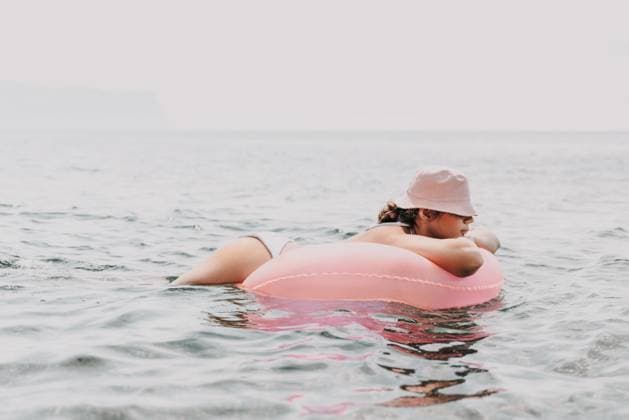 A woman is laying on a pink inflatable raft in the ocean. The scene is peaceful and relaxing, with the woman enjoying the water and the sun. A woman is laying on a pink inflatable raft in the ocean. The scene is peaceful and relaxing, with the woman enjoying the water and the sun, model released, , 96714612.jpg RECORD DATE NOT STATED