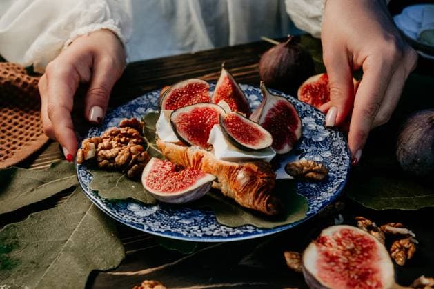 Woman puts plate with camembert cheese croissants, figs. Brie, healthy juicy Woman puts plate with camembert cheese croissants and fig slices. Brie, healthy juicy organic figs. Appetizer breakfast set. Seasonal fruits. High quality photo, 96035494.jpg RECORD DATE NOT STATED