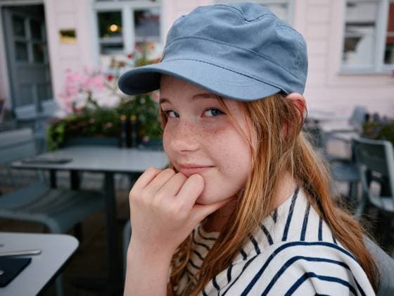 Creative Highlight Symbolbilder Smiling girl wearing a cap posing in outdoor cafe in augsburg, germany Augsburg, Bavaria, Germany CR_OSBJ250918-1810346-01 ,model released, Symbolfoto